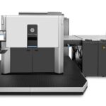 A large printer is shown with the machine in front of it.